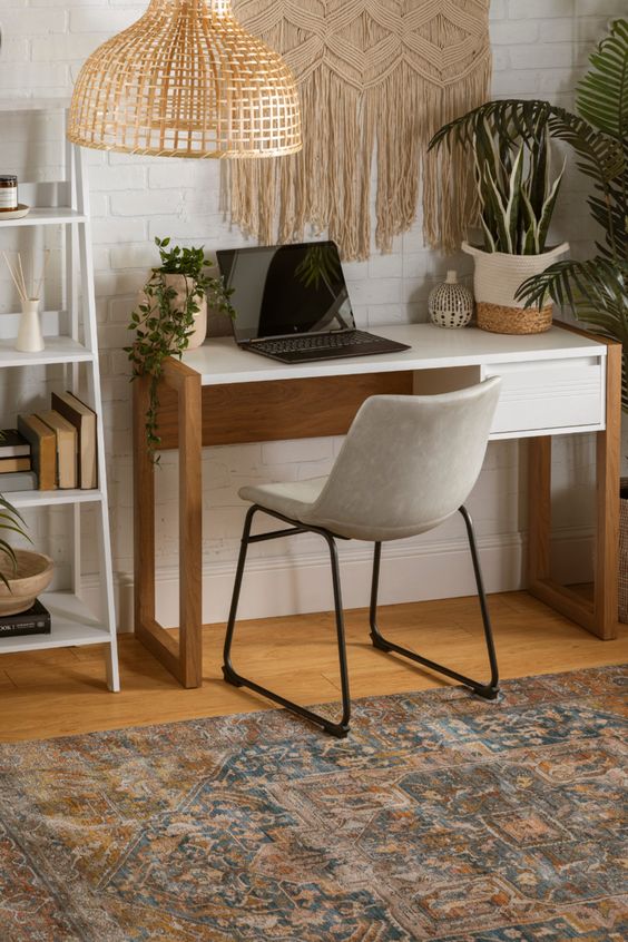 A boho chic home office with a desk, a comfy leather chair, a macrame hanging, a rattan lamp and potted plants.