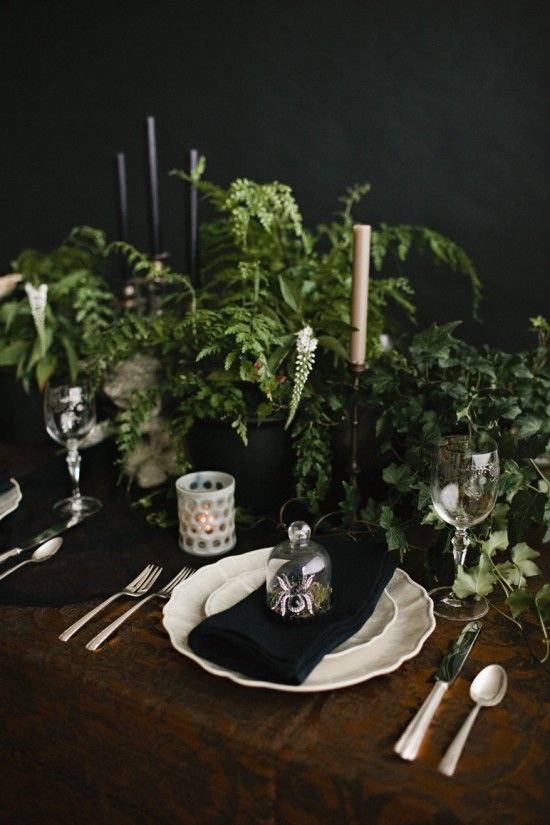 A fresh vintage Halloween tablescape with lots of greenery, black and white candles, white candleholders, porcelain and metallic cutlery is cool.