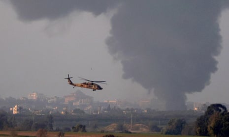 An Israeli army Black Hawk helicopter flies as black smoke billows from Gaza Strip on 1 January 2024.