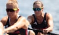 Helen Glover, wearing sunglasses, grips an oar during a rowing race. A teammate is also in the picture, out of focus closer to the camera