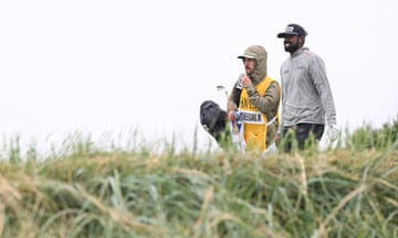 Sahith Theegala walks on the first hole alongside his caddie