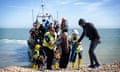 Families are helped ashore on Dungeness beach after rescued in the English Channel.