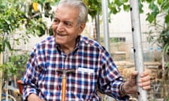 An old man smiles as he sits under a pergola in his roof garden