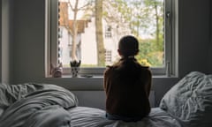 A child looks out of a window from their bed