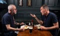 Stuart and Stephen sitting at a wooden table with plates of food and pints of beer on it, in a wood-panelled room