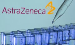 the astrazeneca logo behind a tray of test tubes with a pipette dripping in liquid