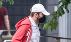 Josh Greally arrives at Barnsley magistrates court: he is wearing a black face mask that covers his nose, mouth and chin plus a white baseball cap, white shirt with large checked pattern, and red hoodie