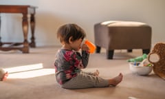 A toddler girl sitting on the floor drinking water from a sippy cup.