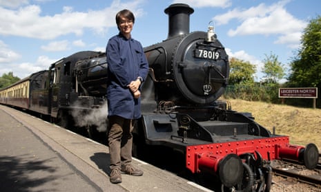 Henry Dyer in a blue smock stood next to a steam locomotive