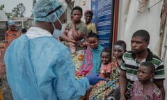 A doctor in a blue uniform and mask speaking with patients outside a treatment centreepicentre of the epidemic that led the World Health Organisation (WHO) to trigger its highest level of alert at the international level on Wednesday. The province of South Kivu records around 350 new cases per week, according to Dr Justin Bengehya, epidemiologist at the provincial health division of South Kivu. Goma, capital of the province of North Kivu, almost surrounded by an armed rebellion and where hundreds of thousands of displaced people are crammed into makeshift camps, fears a large-scale spread due to promiscuity. (Photo by GUERCHOM NDEBO / AFP) (Photo by GUERCHOM NDEBO/AFP via Getty Images)