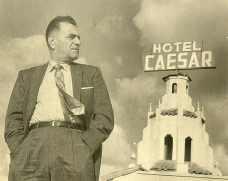 man in suit standing next to tower with the words ‘hotel caesar’ on top
