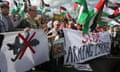 Protesters wave Palestinian flags behind a banner saying 'Stop Arming Israel'