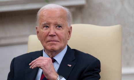 white man wearing navy suit and light blue shirt sitting on a light yellow chair looks up with his hand raised