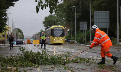 Workers begin to remove fallen tree branches blocking roads and tram routes in Manchester