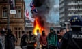 Far-right protesters in Sunderland, 2 August: a group of young men, some wearing balaclavas or face coverings, stand in front of flames and smoke. England and union jack flags are being waved.