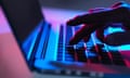 A male hand types on a laptop keyboard at night