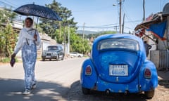 A woman with a parasol walks past a VW Beetle parked in residential neighbourhood of Addis Ababa, Ethiopia