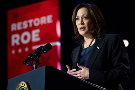 a woman speaks into a microphone next to a sign that says 'restore Roe'