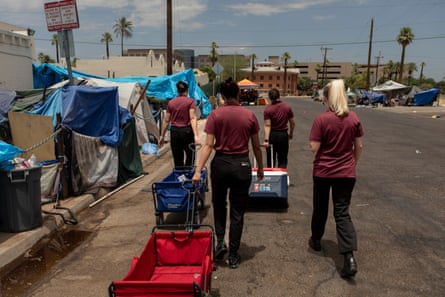 Volunteers with city of Phoenix’s heat response team hand out water and other supplies at an encampment during the heatwave.