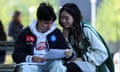 A boy and a girl smile while looking at a piece of paper.