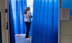 A health worker walks between curtains on an NHS hospital ward