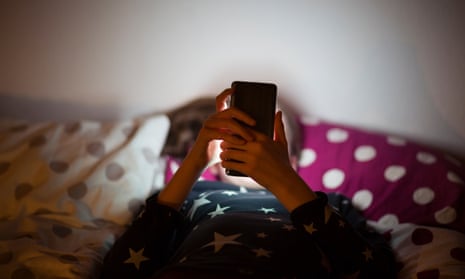 Girl lying on bed at night and using a mobile phone