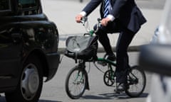 A city gent rides a folding cycle among traffic in central London.