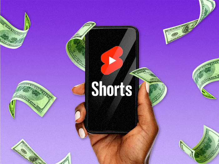 Hand holding phone with YouTube shorts logo and money flying around 4x3