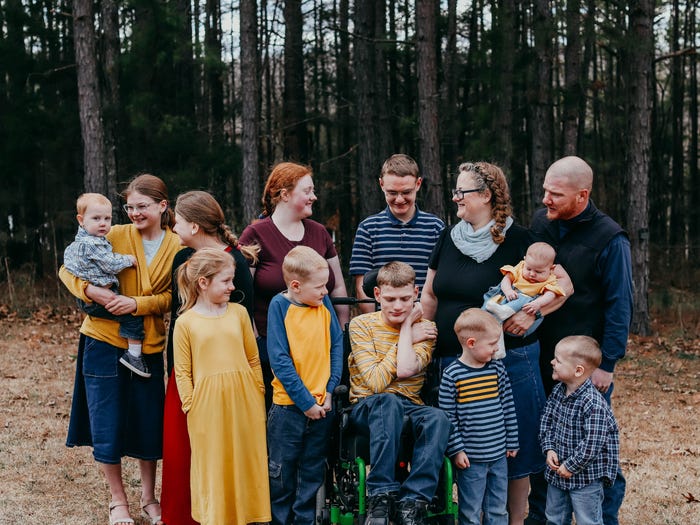 the tanner family posing for a photo together in a wooded area outside