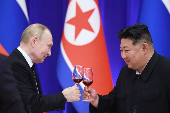 Vladimir Putin and Kim Jong Un smiling and holding up glasses of red wine.