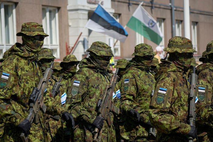 A group of Estonian soldiers in uniform hold rifles and march in formation during a victory day parade in Viljandi, Estonia in June 2023.