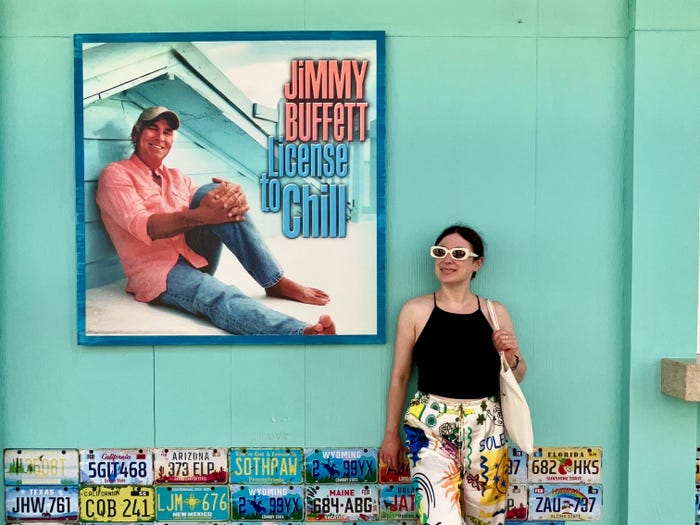 simone posing next to a poster of jimmy buffet's license to chill album at Margaritaville resort