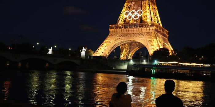 Spectators view the Eiffel Tower and Olympic rings along the Seine river on July 21, 2024