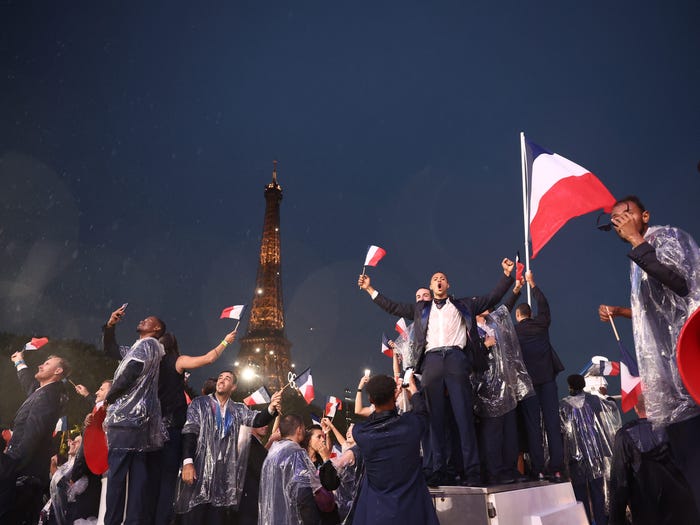 french olympians posing with the eiffel tower in the background at the Paris 2024 opening ceremony