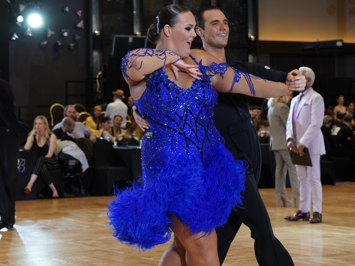 Charlott Page in a blue sparkly dress, competing at a ballroom competition with her coach Gian DiFranco.