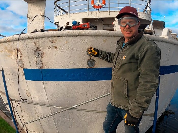 A man at the stern of the Aurora cruise liner, wearing safety goggles and gloves.