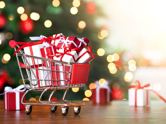 Small shopping with wrapped gifts inside against a Christmas tree in the background