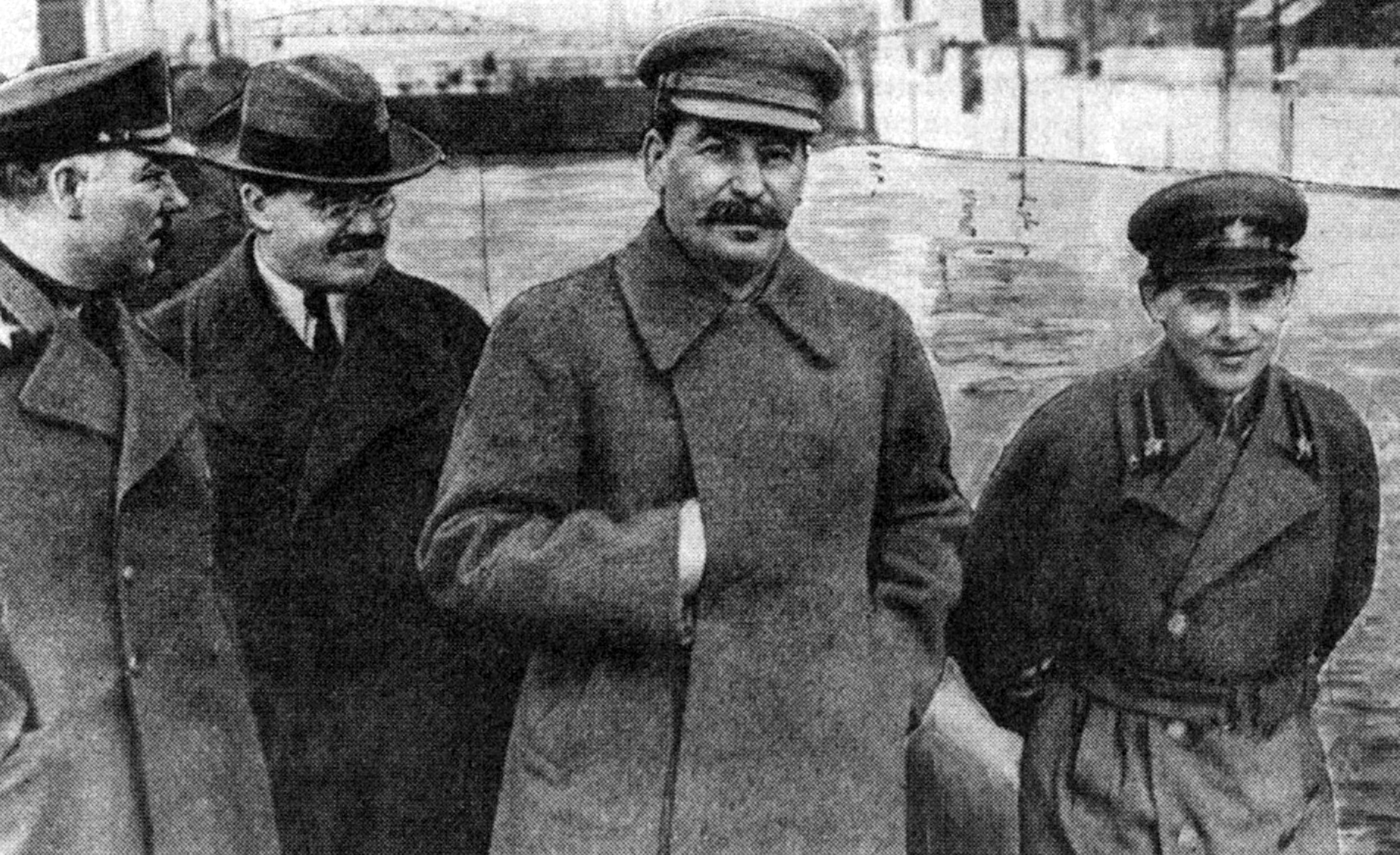 A black and white photo shows Joseph Stalin, Nikolai Yezhov and other Soviet officials. 