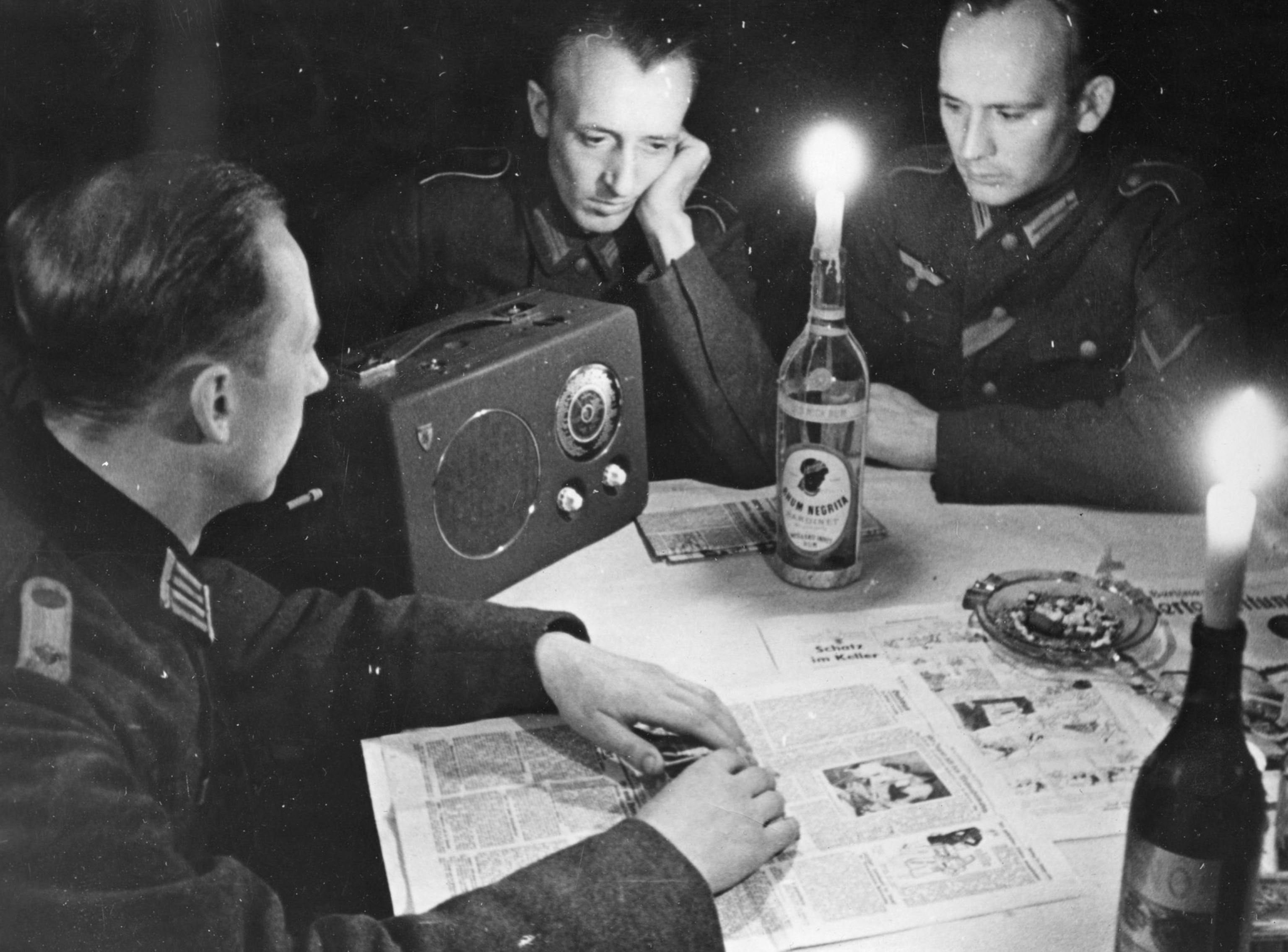 Mensit around a table with a small light listening to the radio.