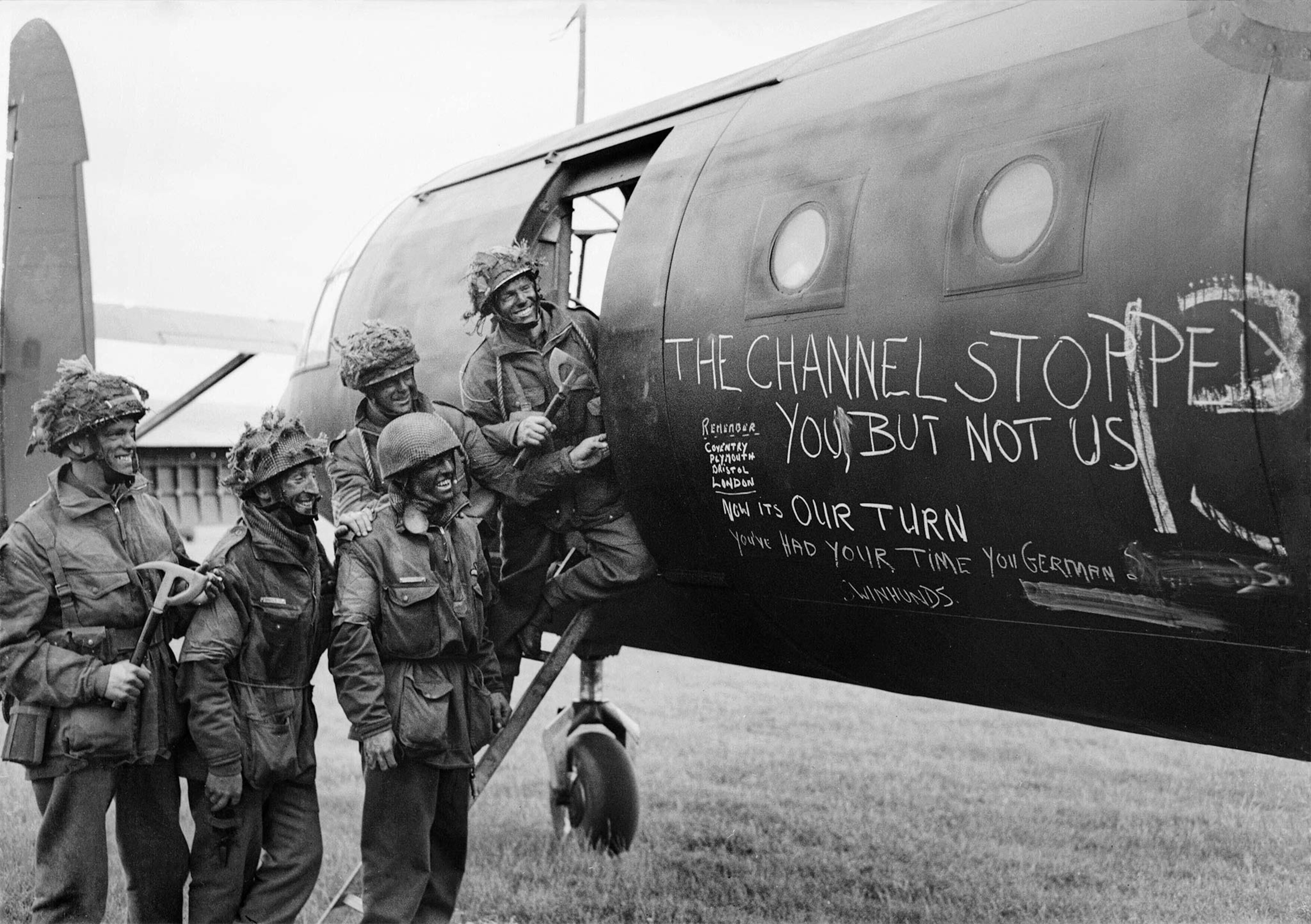 Troops inspect the message, "The channel stopped you, not us," on their Horsa glider at an airfield