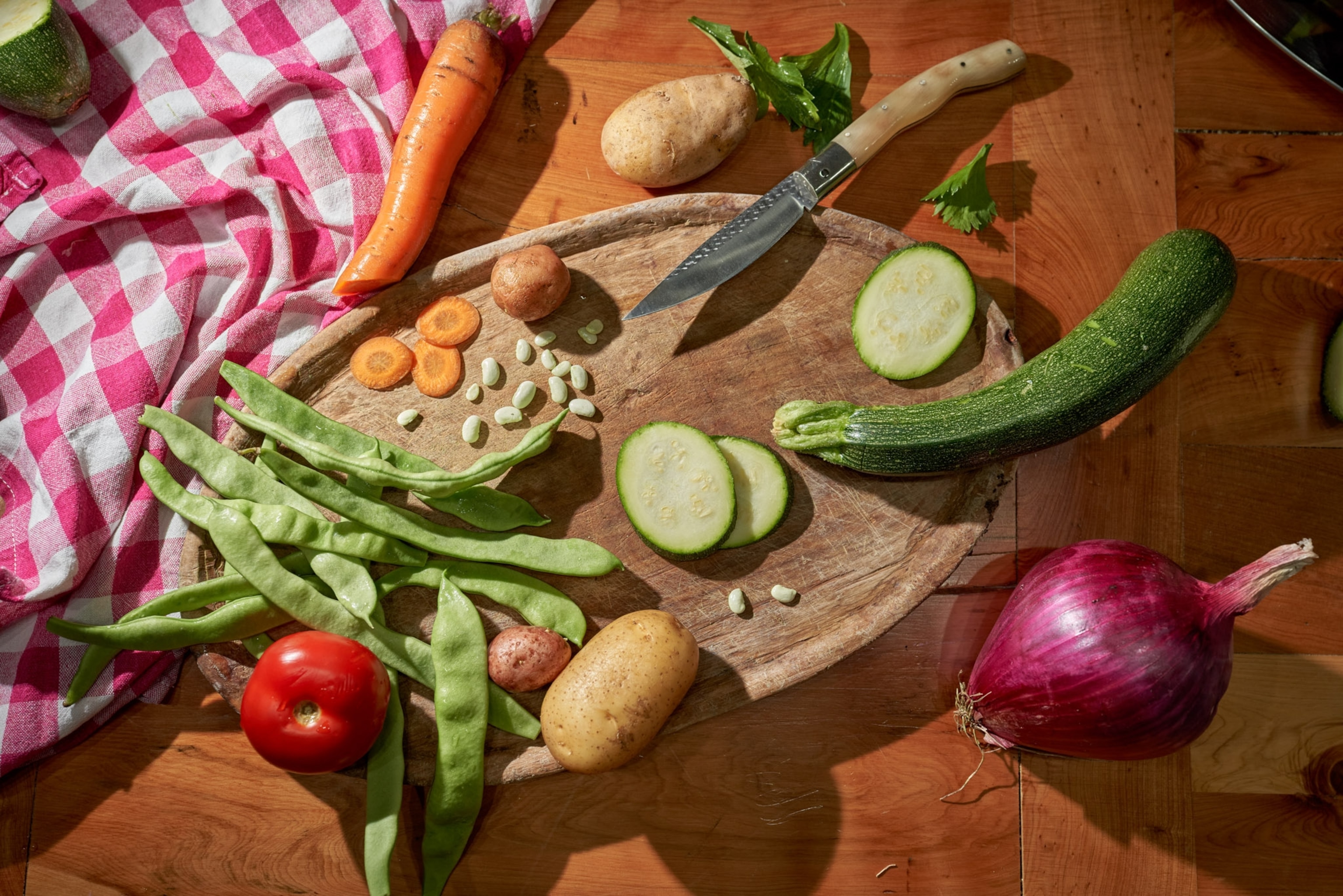 A variety of vegetables lay on and around a cutting board.