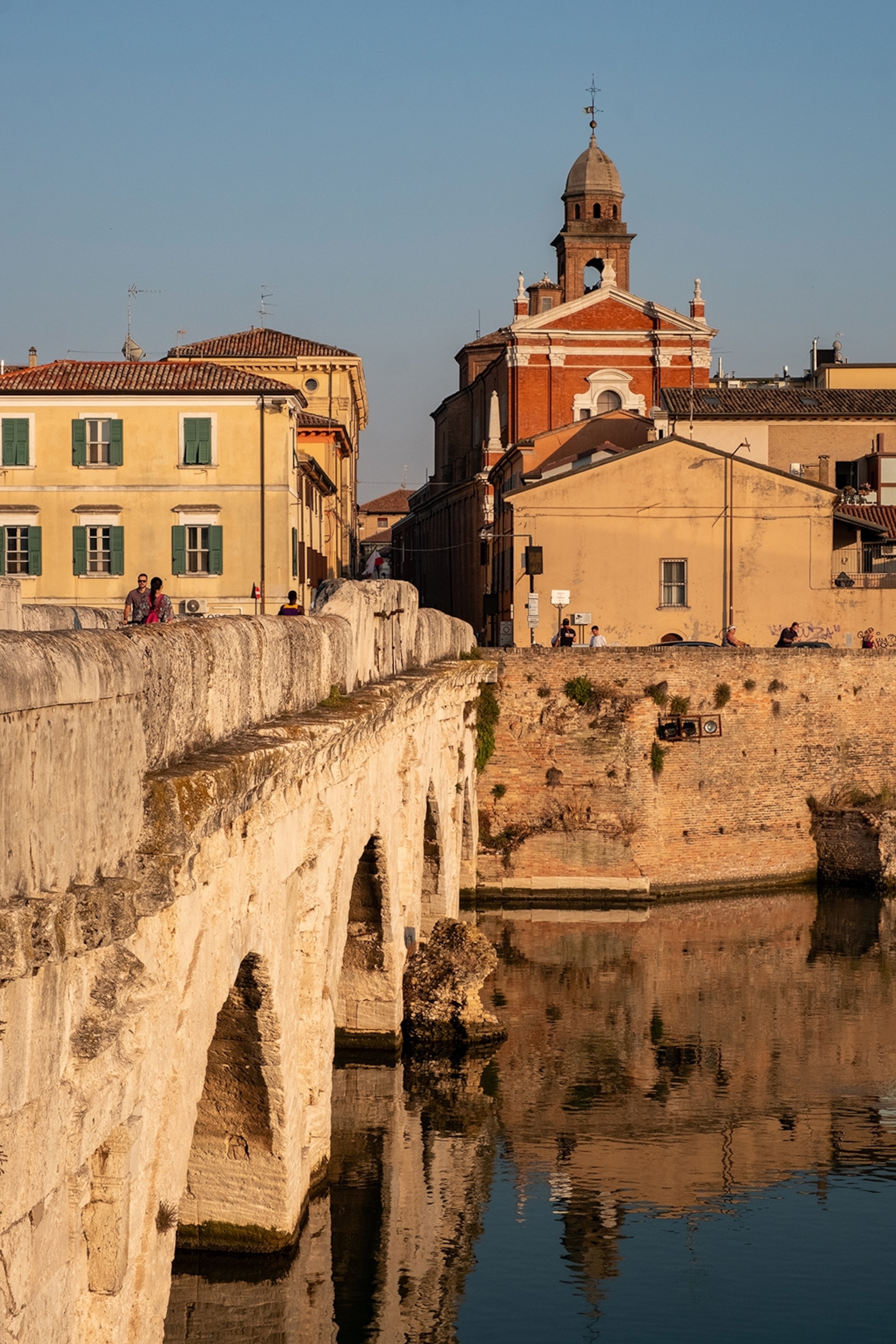 Historic stone bridge with pastel-coloured buildings alongside