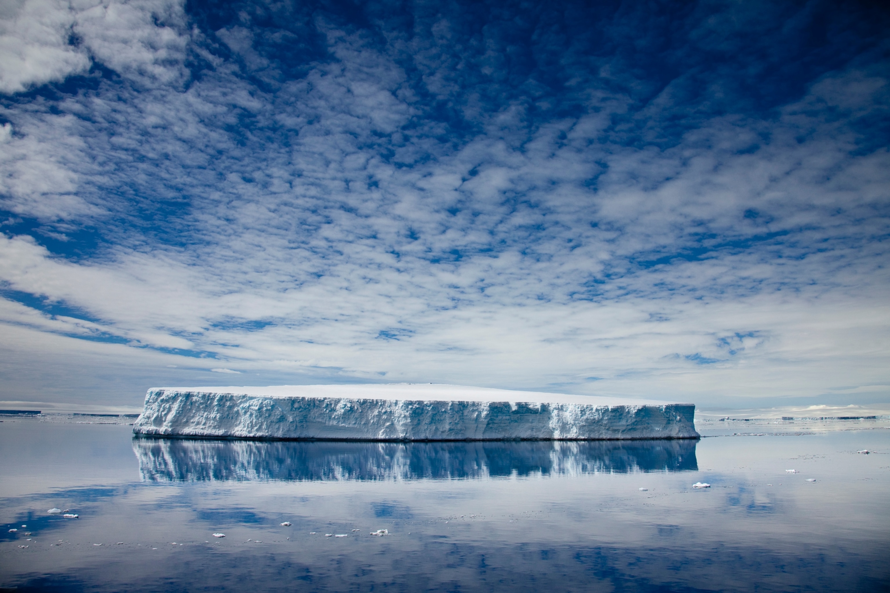 Tabular iceberg reflected in still water.