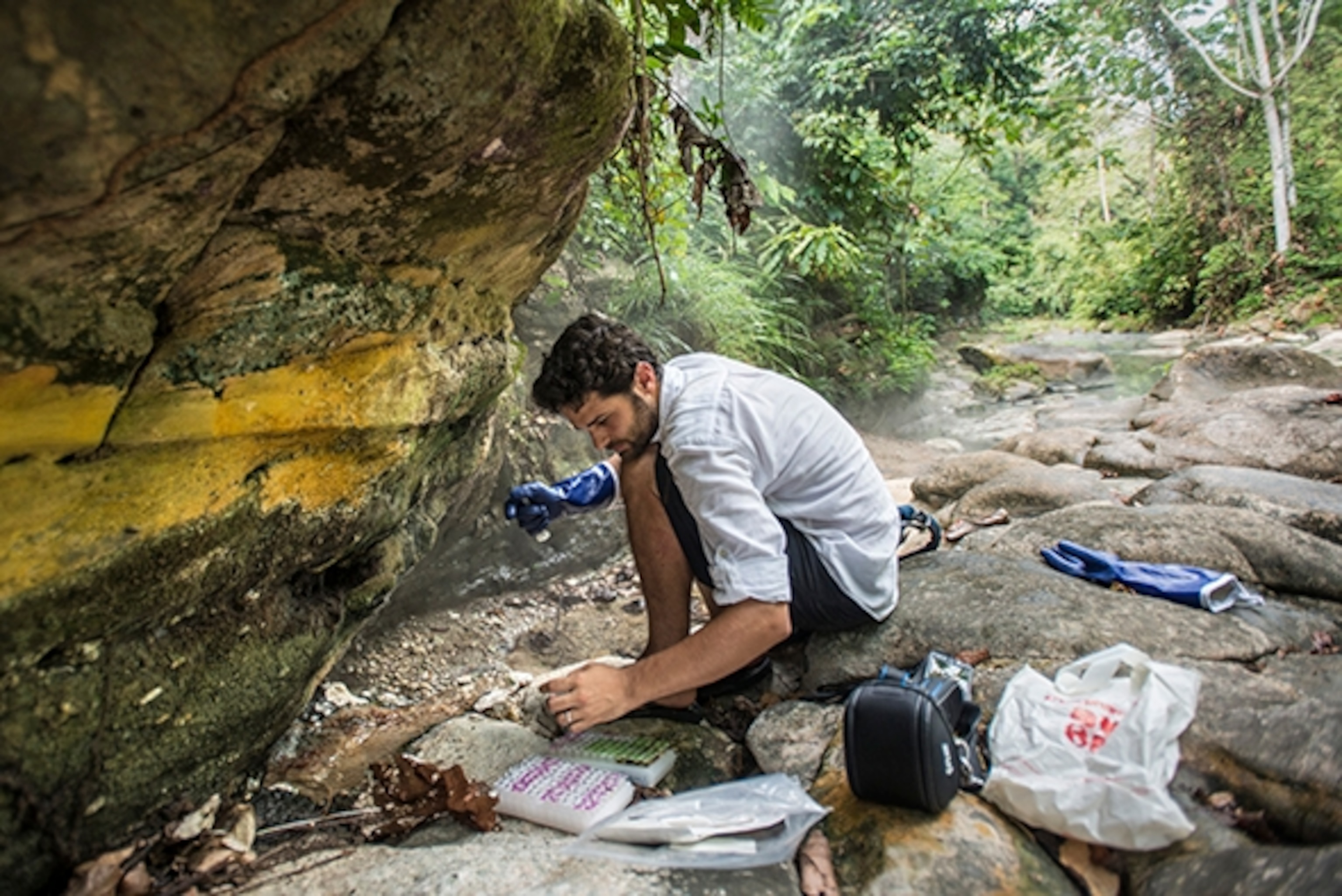 To understand the processes and mechanisms that result in the Boiling River, Andrés has been conducting geochemical studies, with yearly field sampling, for five years. He studies the water’s isotopic composition, as well as elements present in the samples in order to characterize the waters and understand how they are interacting with the local geology. Here, Andrés is taking water samples at the Smoking Walls— where steaming, fault-fed thermal springs along the Boiling River veil the cliff-face in vapor; Photograph by Devlin Gandy