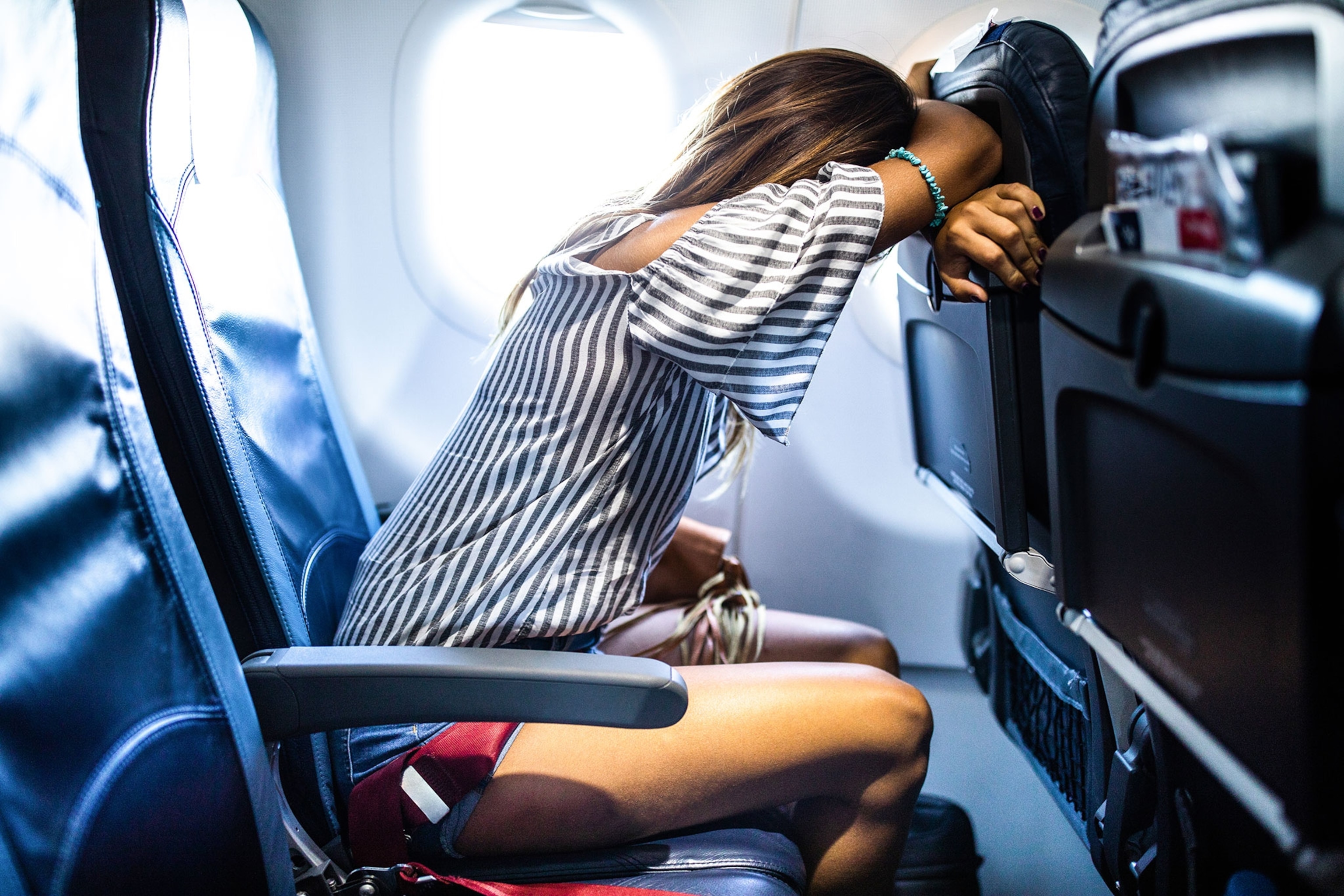 Woman with obscured face taking a nap while traveling by airplane.