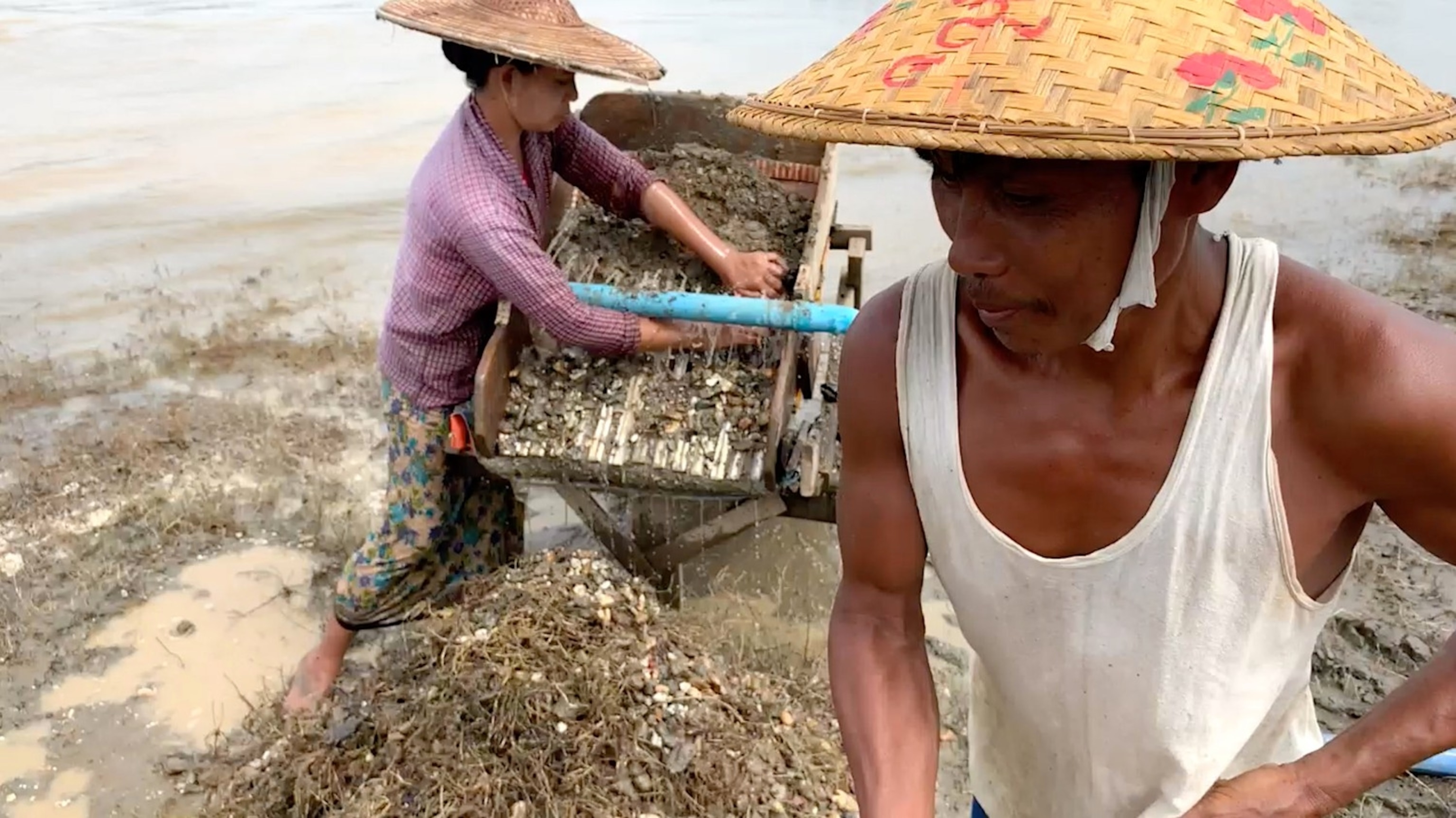 Do Toe, left, and Than Ngwe prospect for crumbs of gold along the Chindwin River in northern Myanmar. The husband-and-wife team earns about three dollars a day.