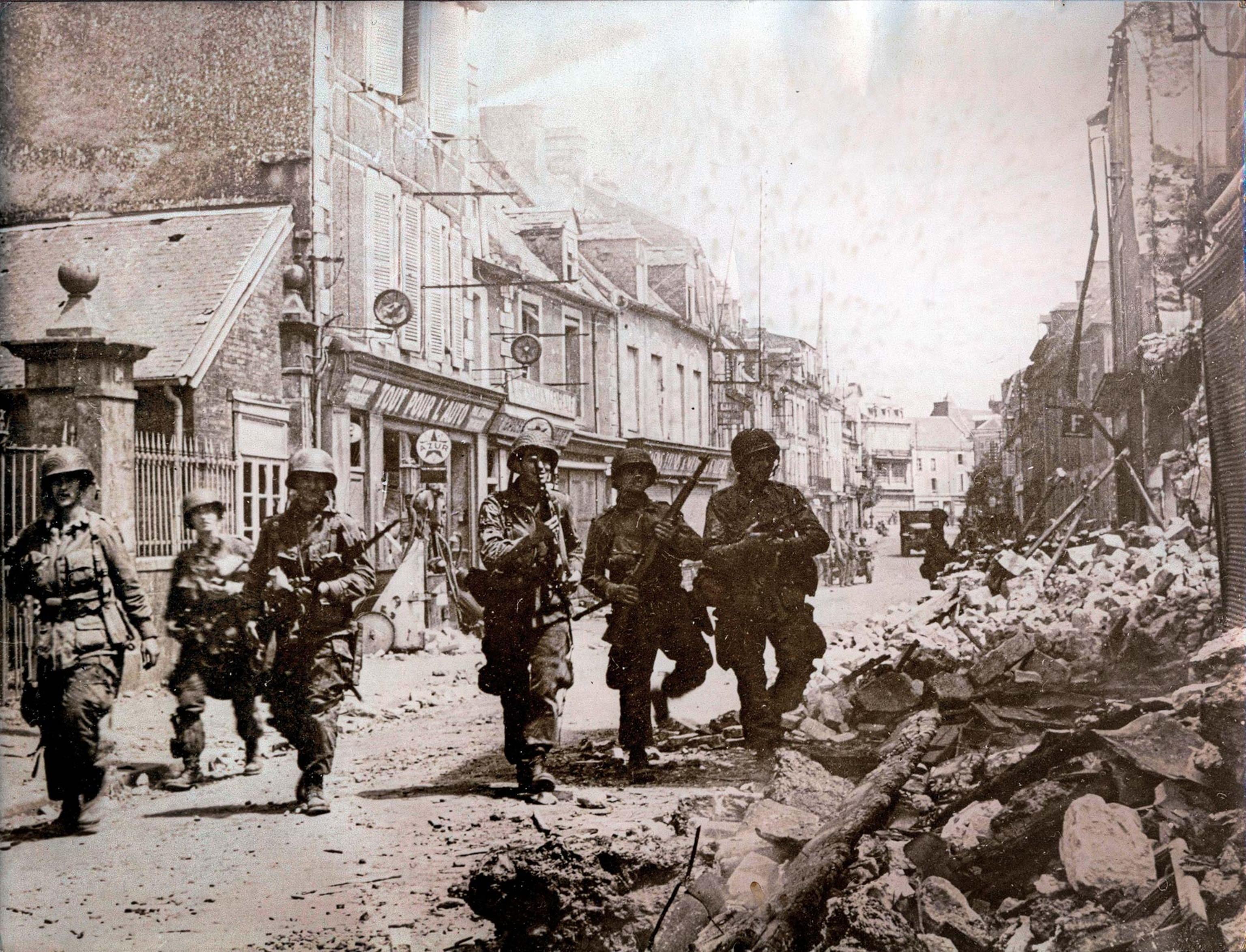 Troops patrol the streets of a war-torn town in Normandy