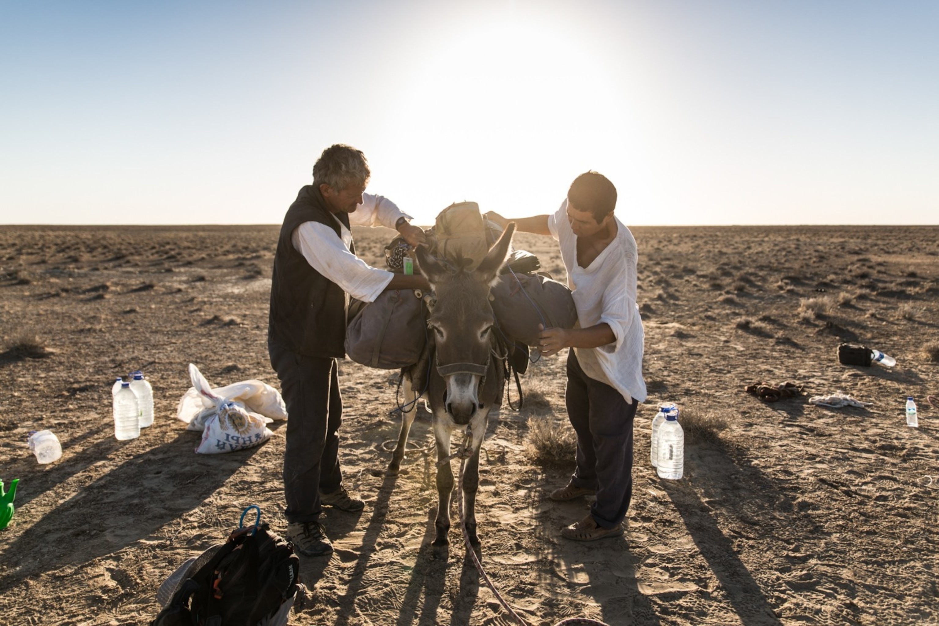 Tanatar “Tolik” Bekniyazov (right) and Paul Salopek adjust a cargo donkey’s load in the Kyzyl Kum Desert in Uzbekistan.