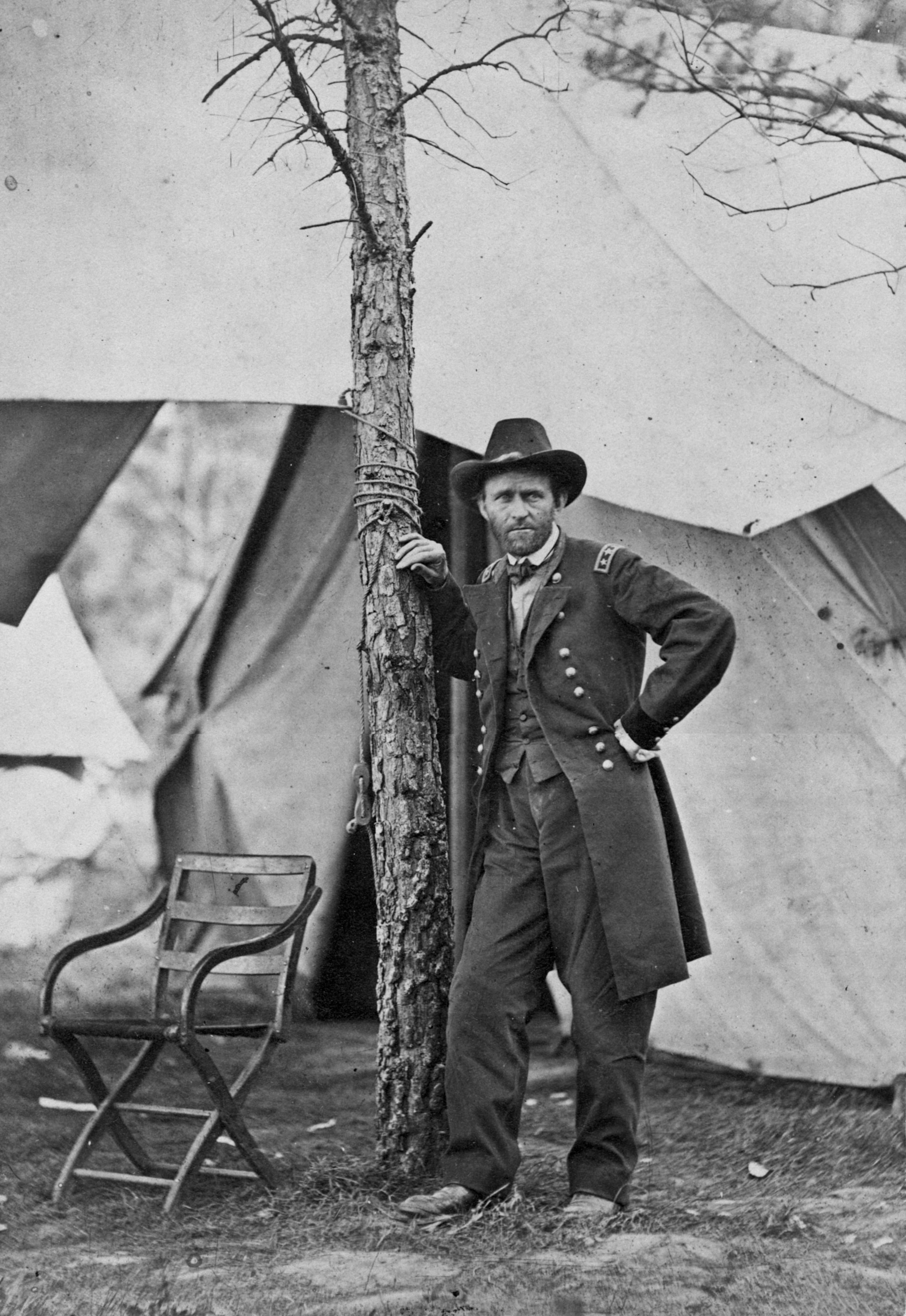 A black and white photo from June 1864 shows Grant standing next to a tree in Cold Harbor, Virginia.