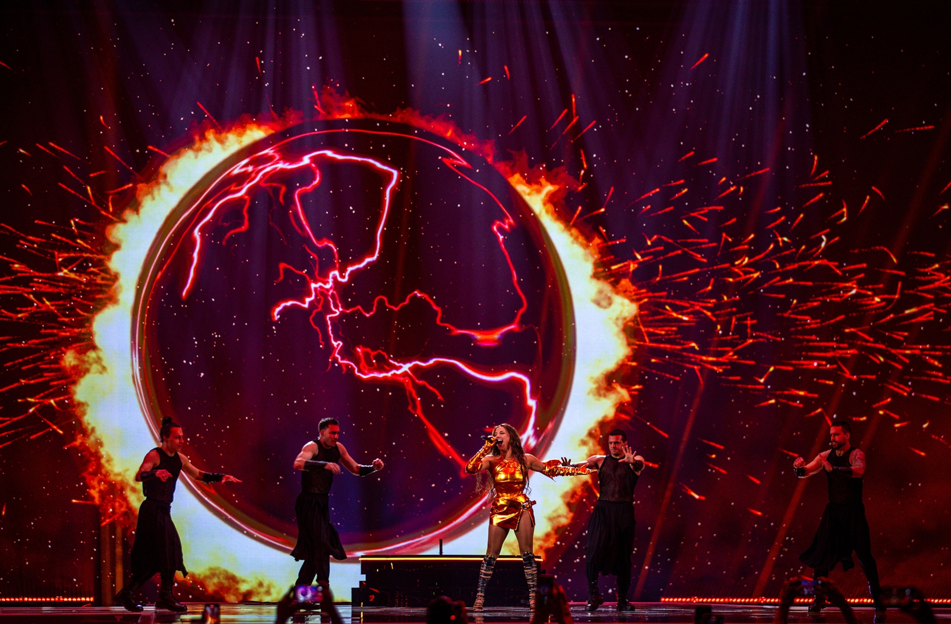 A glowing red earth outlines parts of europe as a design as a singer performs.